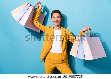 Portrait of attractive cheerful woman carrying new things gifts having fun isolated over bright blue color background