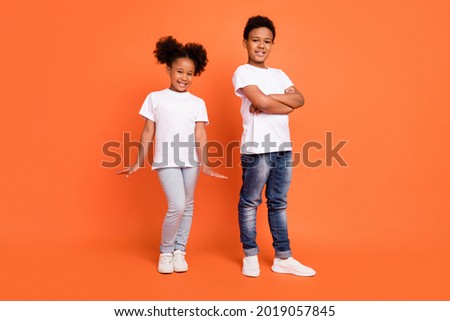 Full length photo of little cool girl boy crossed arms wear white t-shirt jeans sneakers isolated on orange background Royalty-Free Stock Photo #2019057845