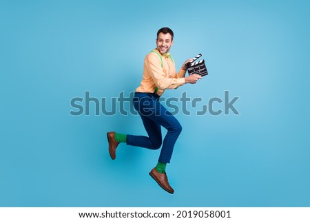 Photo of funny producer guy jump hold clapboard run wear suspenders shirt isolated blue color background