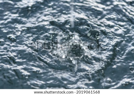 Large raindrops are falling. Blurred background with water, out of focus