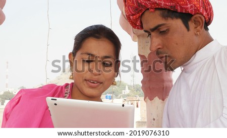 An Indian couple in Indian traditional clothing looking at the tablet