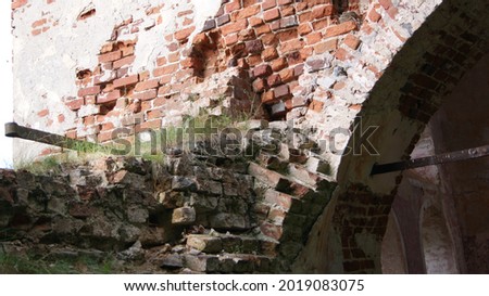 Crumbling bricks of an old, abandoned church, overgrown with bushes