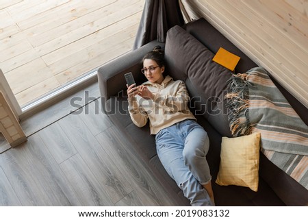 A girl during quarantine communicates in social networks lying on the couch. High quality photo