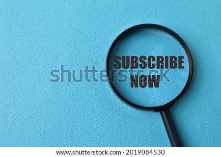 Magnifying glass with phrase SUBSCRIBE NOW isolated on blue background