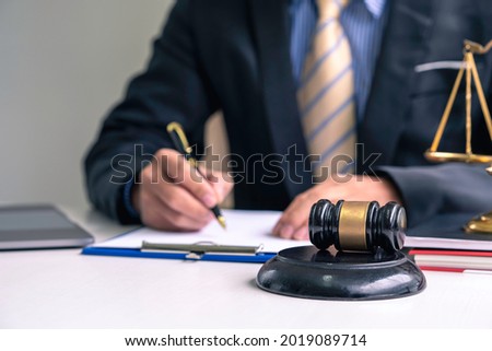 lawyers discussing contract papers with brass scale on the desk in the office. Law, legal services, advice, justice, and law concept 