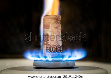 Russian ruble is burning in the fire. concept the rise in the price of gas in Russia. a bill of 5000 rubles burns in a fire on a gas stove. Expensive gas supply Royalty-Free Stock Photo #2019112406