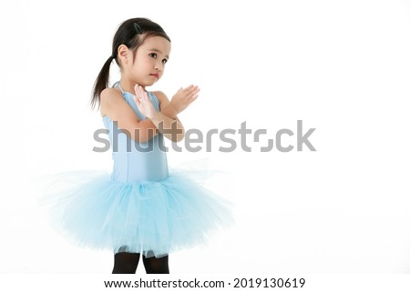 Portrait isolated studio shot of small beautiful Asian kindergarten pigtails ballerina dancer girl in blue tutu ballet dress black legging standing posing in cute and active gestures.