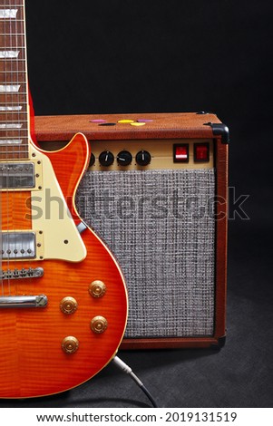 Amplifier for guitar with honey sunburst guitar on the black background. 