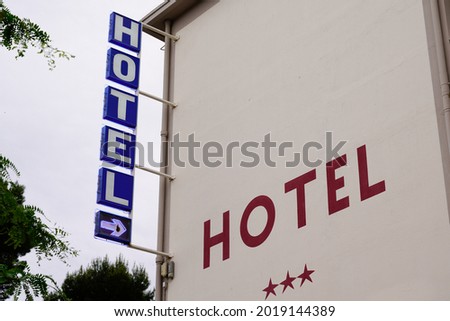 Hotel light arrow sign blue and red text and three stars on Building in tourist city