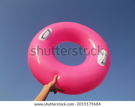 Pink inflatable tube in the girl's hand against the blue sky