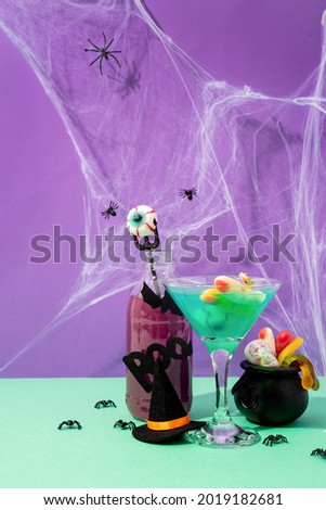 Happy Halloween concept. Scary colorful purple Halloween cocktails with party decorations on purple background