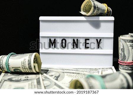 Lightbox board with the word MONEY in black letters around Us dollars banknotes. Finance background. Business, financial success and making money concept. Business budget of wealth and prosperity 