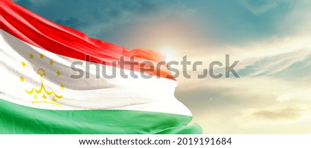 Tajikistan national flag waving in beautiful sky.