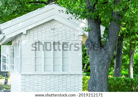 White wooden kiosok house for trade in the park. The windows are closed with paper.