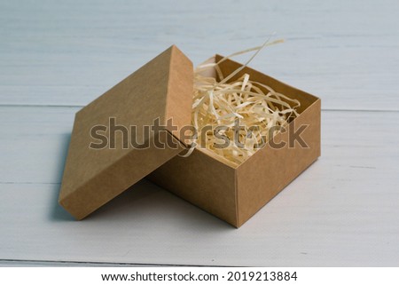 Craft gift box with light wood filler on wooden background with copy space.