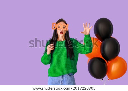 Beautiful young woman with balloons and Halloween decor on color background