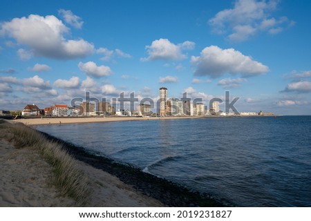 Waterfront, dunes and view on Vlissingen city with sandy beach on sunny sunset, Zeeland, Netherlands