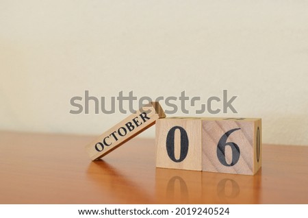 October 6, Date design with calendar cube on wooden table and white background.