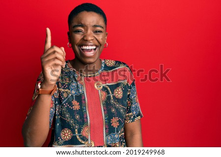 Young african american woman wearing african style pointing finger up with successful idea. exited and happy. number one. 