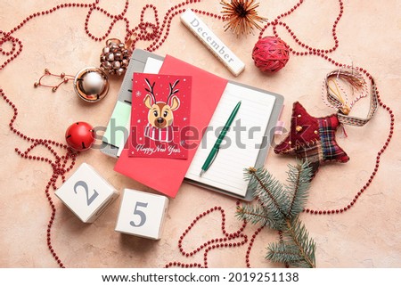 Beautiful composition with greeting card for New Year celebration and notebook on color background