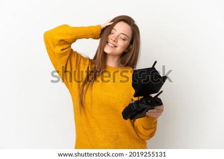 Teenager girl holding a drone remote control over isolated white background smiling a lot