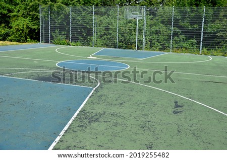 multifunctional outdoor playground for ball games at school. green artificial turf from a plastic carpet with lines. basketball hoops and soccer goals. around the grabbing high net and guardrails