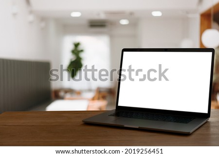Front view of laptop on wood table in cafe blurred background.