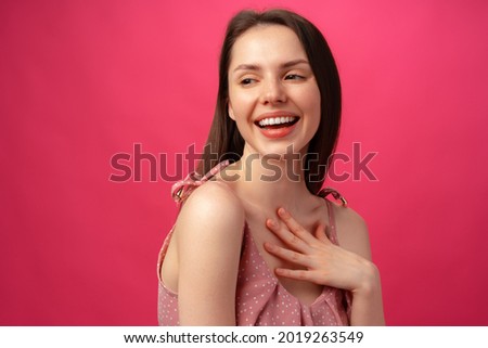 Cheerful happy young beautiful girl smiling and laughing against pink background