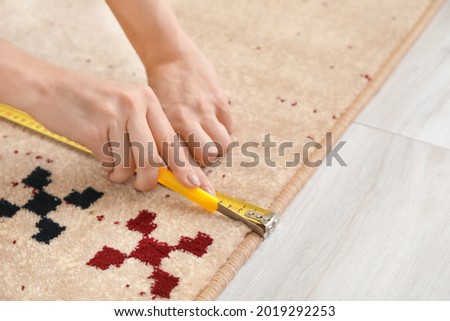 Woman with measuring tape cutting carpet Royalty-Free Stock Photo #2019292253