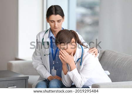 Female doctor calming her stressed colleague in clinic Royalty-Free Stock Photo #2019295484