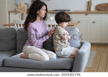Loving mother trying to make peace with stubborn offended boy kid sitting frowning and with crossed arms ignoring caring mom. Mummy feeling sorry for misunderstanding with child. Parenthood problems Royalty-Free Stock Photo #2019301796