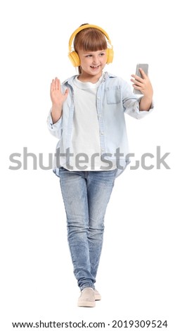 Little girl with mobile phone and headphones on white background
