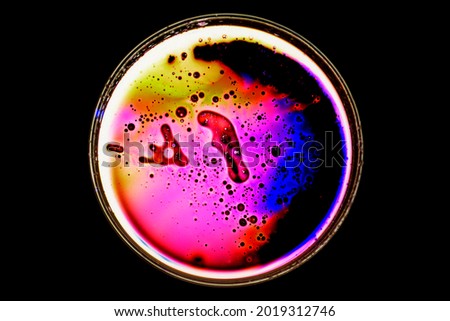 Petri dish with droplets and bubbles infrared with light. Colourful liquid in a petri dish with a black background. Taken with a Macro lens in the studio.