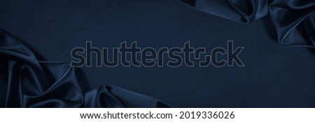 Beautiful dark blue silk satin background. Soft folds on shiny fabric. Luxury background with copy space for text, design. Web banner. Flat lay, top view table.Birthday, Christmas, Valentine's Day. Royalty-Free Stock Photo #2019336026