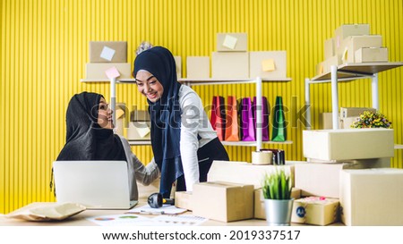 Muslim two asian woman freelancer sme business online shopping working and checklist order with cardboard box on table at home - Business online shipping and delivery concept
