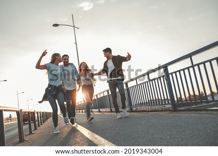 Young people hangout at the city street.They walking over the bridge and joying in autumn sunset.	 Royalty-Free Stock Photo #2019343004