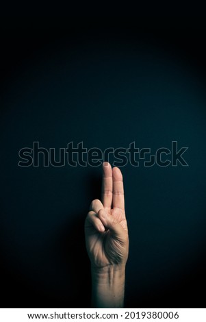 Dramatic colour image of male hand demonstrating ASL American sign language letter U with empty copy space for editors