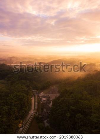 Drone photo of the Indonesian rural landscape with river and forest in the morning on foggy weather