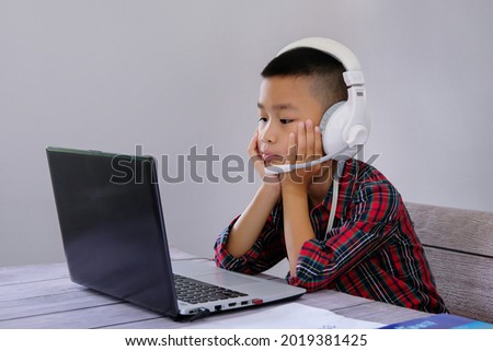 boy sitting in front of laptop screen Study online at home, plug in headphones, listen attentively to study. Listen to the teacher online teaching concept
