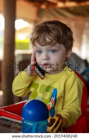 Blond blue eyed little boy talking on cell phone