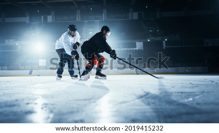 Ice Hockey Rink Arena: Two Young Players Training, Learning Stick and Puck Handling. Athletes Learn how to Dribble, Attack, Defend, Protect, Possesion, Drive the Puck.