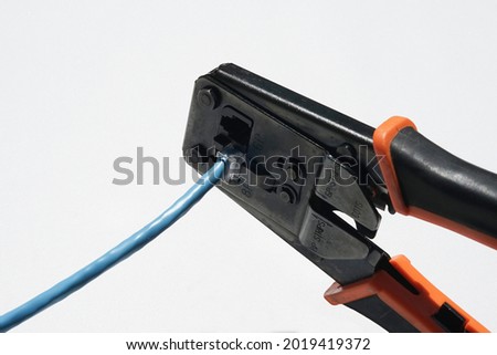 Network crimping pliers with RJ 45 connector being connected blue color utp cable on isolated white background Royalty-Free Stock Photo #2019419372