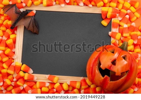 Nostalgic American tradition, iconic trick or treat sweets and Halloween backgrounds concept with many candy corn pieces, chalkboard with copy space, Jack o lantern and bat