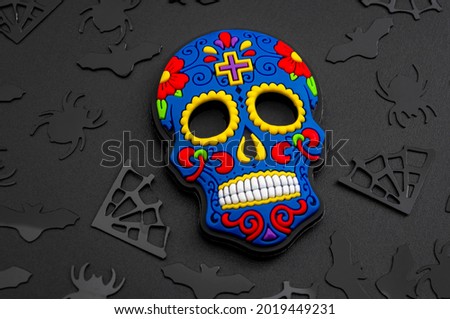Halloween backgrounds, Mexican culture and Dia de los Muertos (day of the dead) concept with colorful skull and black confetti isolated on dark background