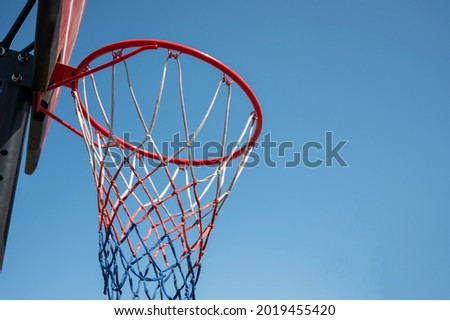 Bottom view of an empty basketball basket against the blue sky