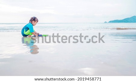 Happy little girl have fun in sea surf on white sand beach. Happy child and summer vacation concept. Soft focus. Copy space.