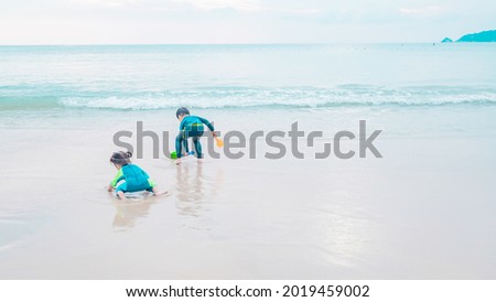 Happy kids have fun in sea surf on white sand beach. Happy child and summer vacation concept. Soft focus. Copy space.