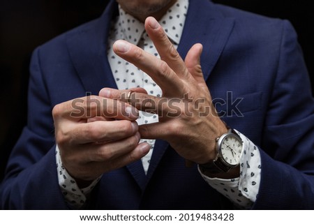 a man puts a wedding ring on his finger, the concept of cheating on a married man. Royalty-Free Stock Photo #2019483428