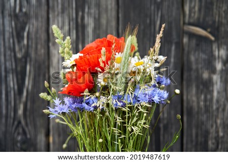 Bouquet bunch wild flowers chamomile poppy cornflower rye wooden background