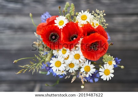 Bouquet bunch wild flowers chamomile poppy cornflower rye wooden background